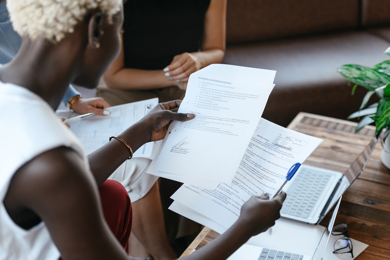 From above of crop anonymous African American female comparing data in papers at table of office